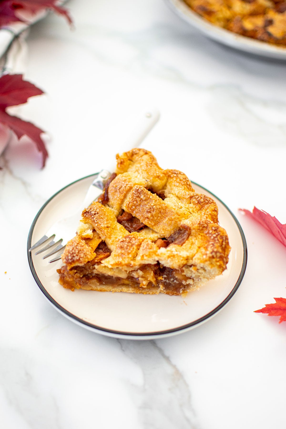 slice of brown sugar honey apple pie on a white plate on a marble counter.