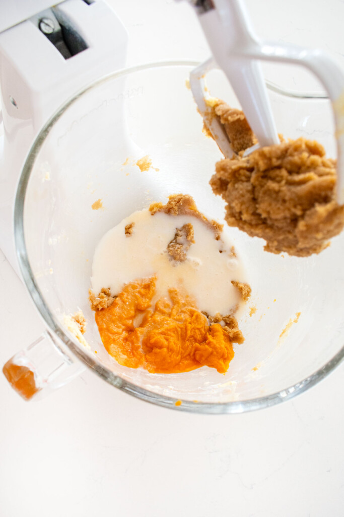 ingredients for cinnamon sweet potato bread in a glass mixing bowl on a white marble counter.