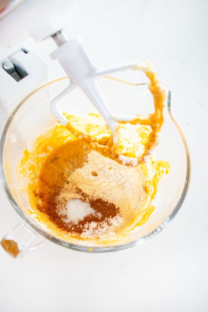 ingredients for cinnamon sweet potato bread in a glass mixing bowl on a white marble counter.