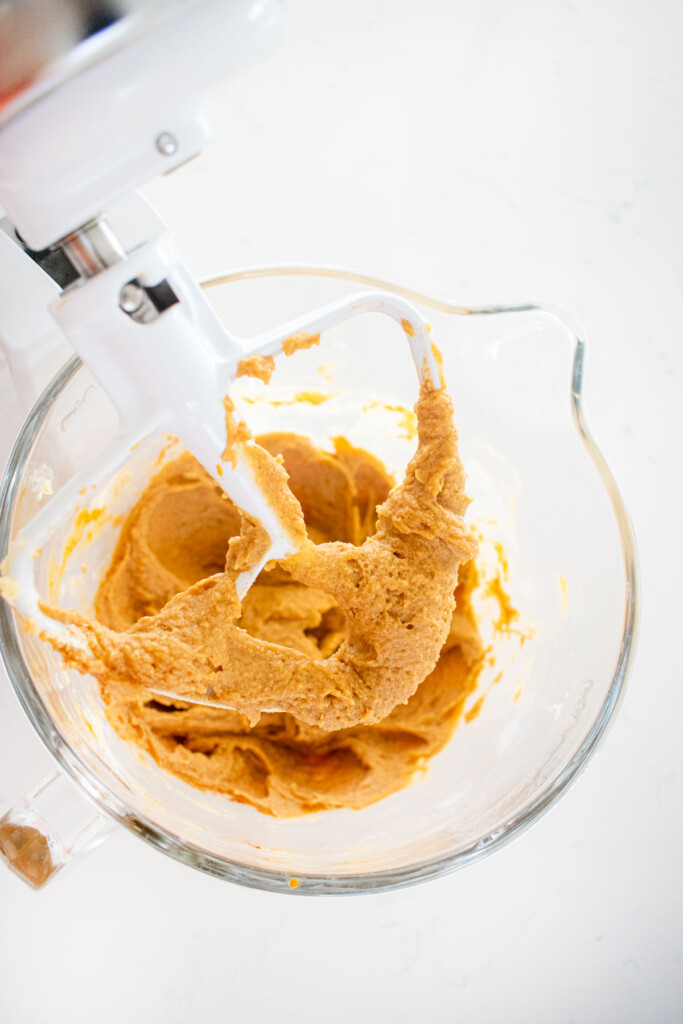 cinnamon sweet potato bread batter in a glass mixing bowl on a white marble counter.