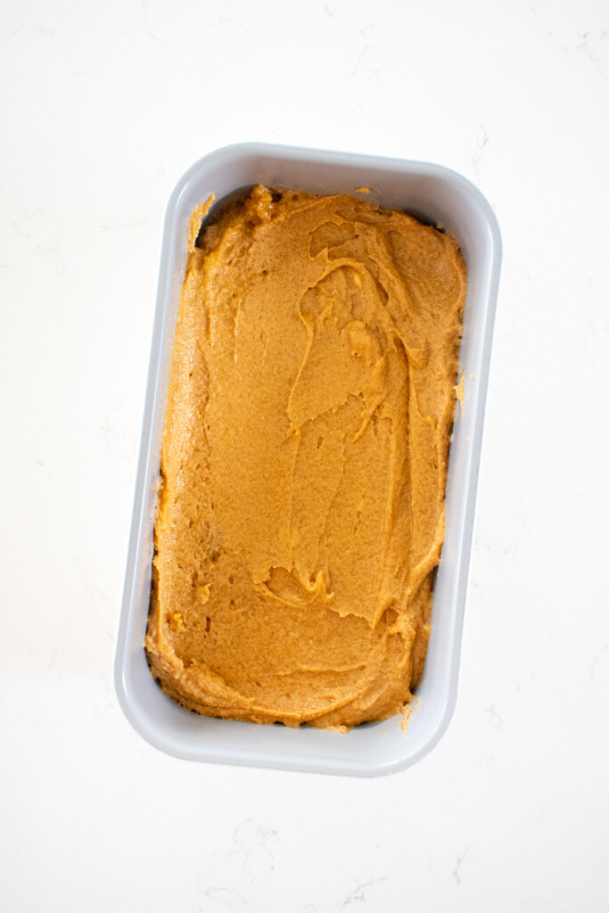 cinnamon sweet potato bread batter in a loaf pan on a white marble counter.