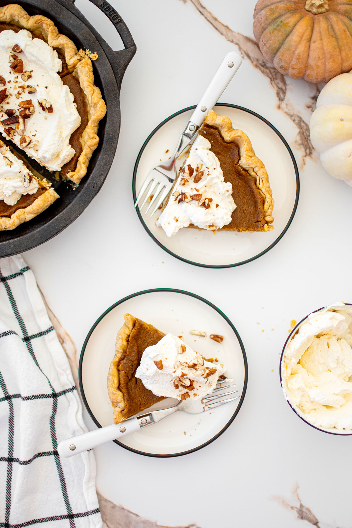 two plates with slices of eggless sourdough pumpkin pie on a white marble counter.