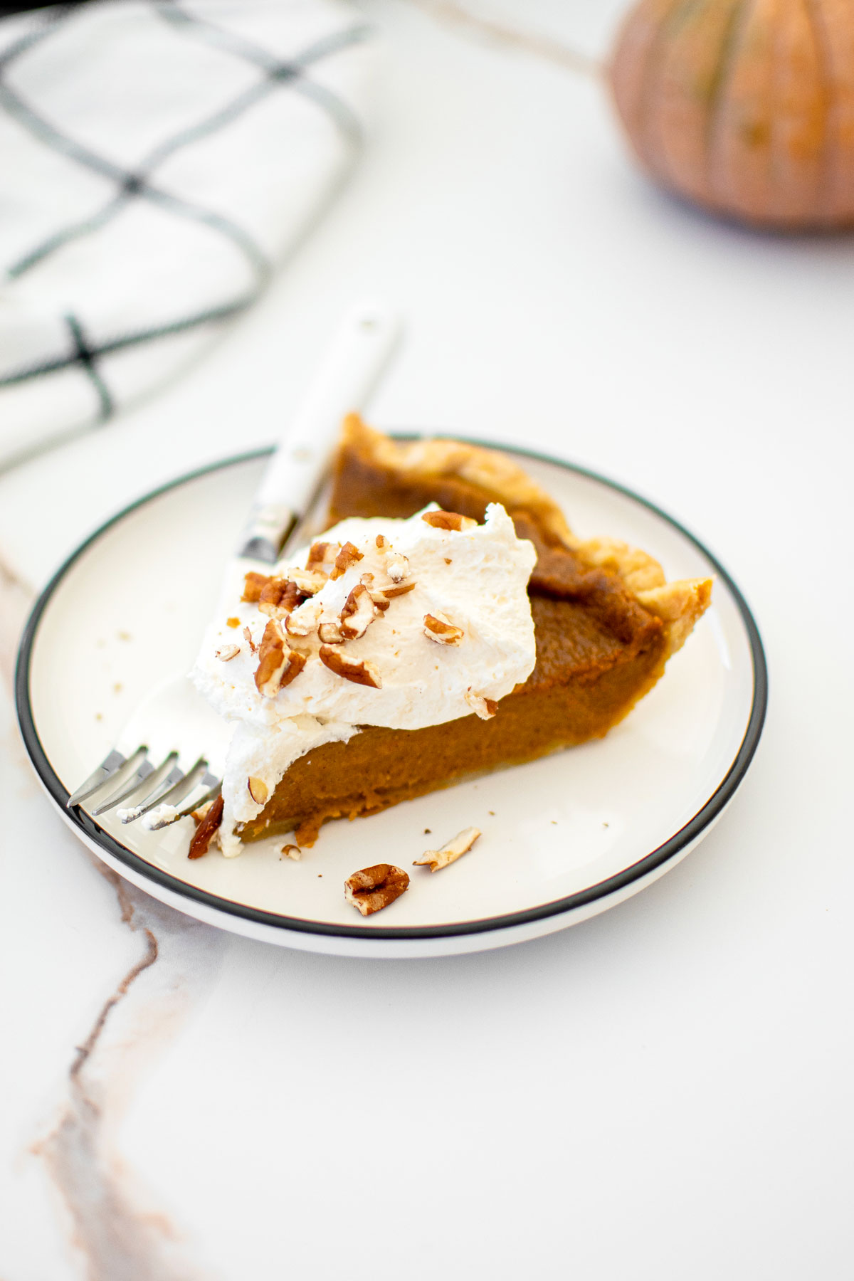 eggless sourdough pumpkin pie slice on a plate on a white marble counter.