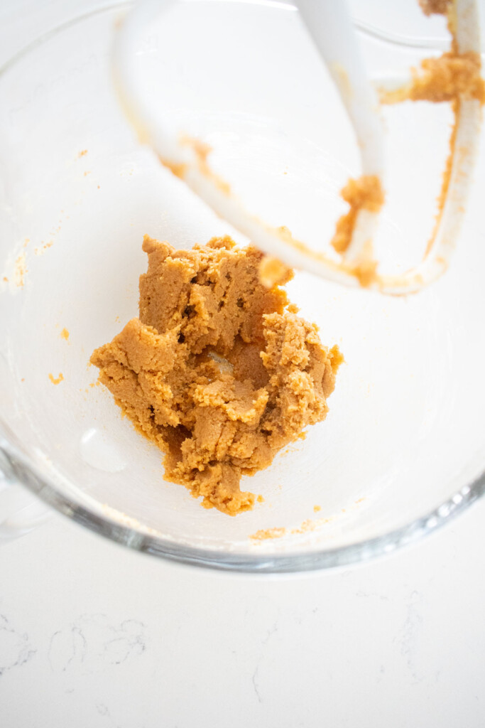 creamed butter and sugar in a glass mixing bowl on a white marble counter.