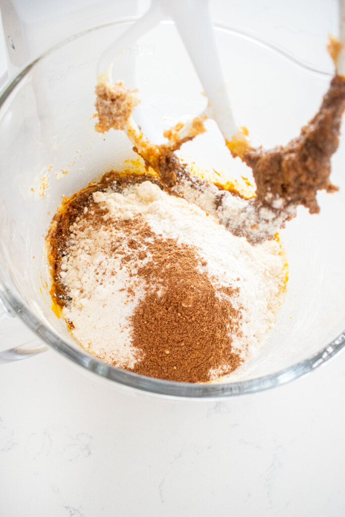ingredients for gluten free gingerbread cookies in a glass mixing bowl on a white marble counter.