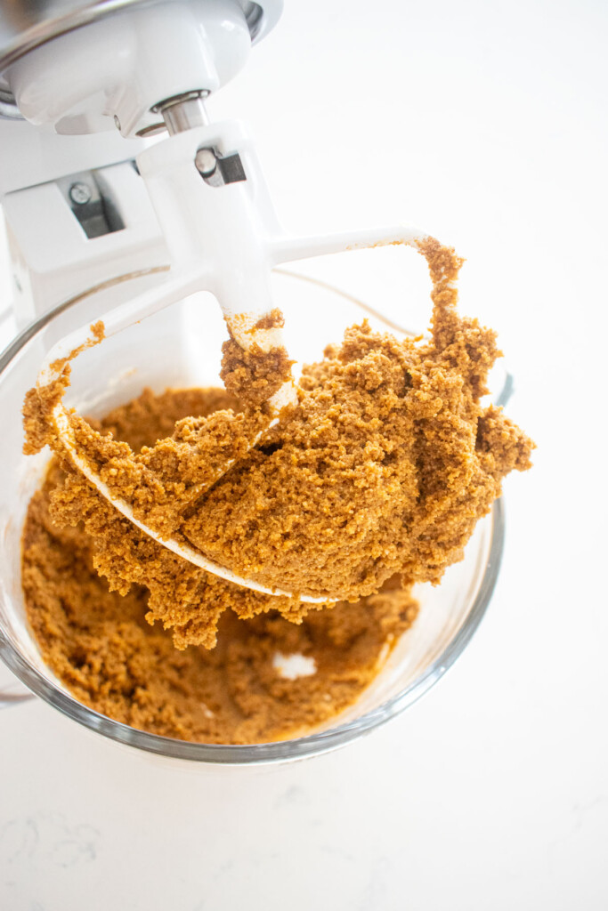gluten free gingerbread cookie dough in a glass mixing bowl on a white marble counter.