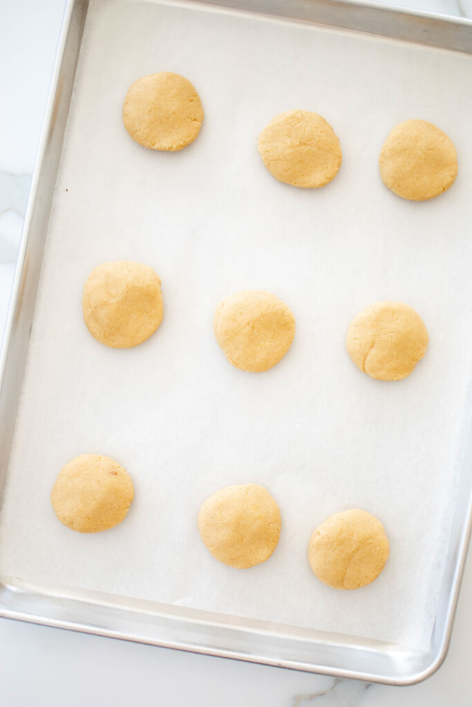 holiday sugar cookie dough on a baking sheet on a white marble counter.