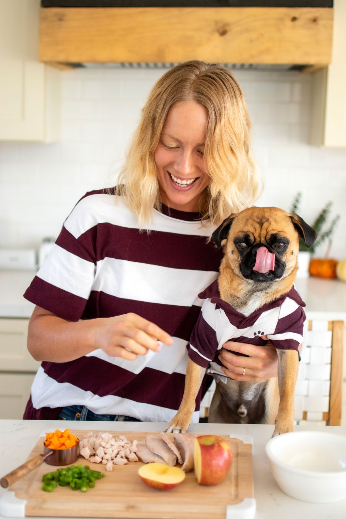 woman and pug in the kitchen making thanksgiving dinner for dogs at the kitchen counter.