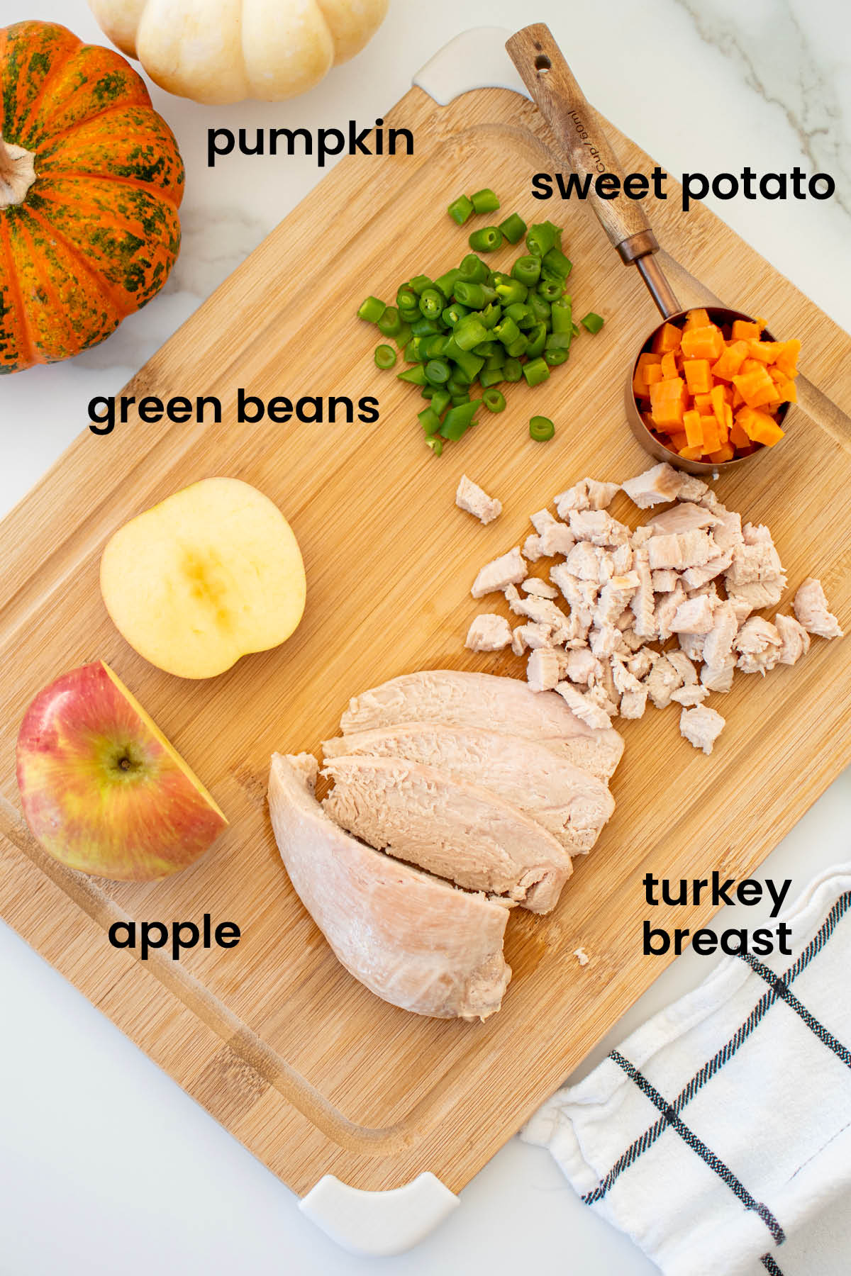 individual ingredients for maple cream cheese spread laid out on a wood cutting board on a marble countertop.