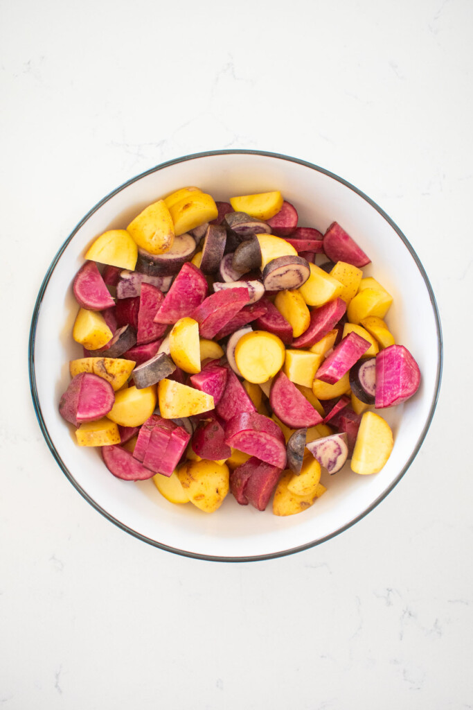 bowl of chopped fingerling potatoes on a white marble counter.