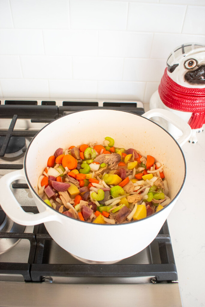 turkey carcass soup with bone broth being simmered in a dutch oven on the stovetop.