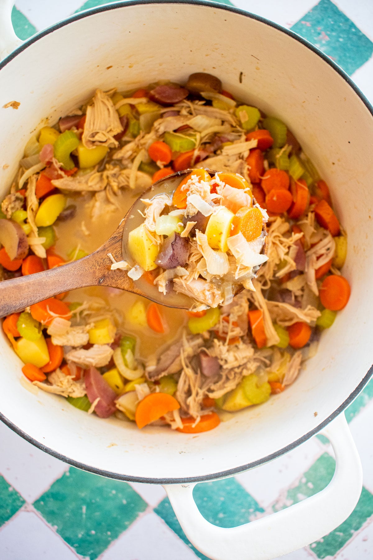 turkey carcass soup in a dutch oven with a wood soup ladel.