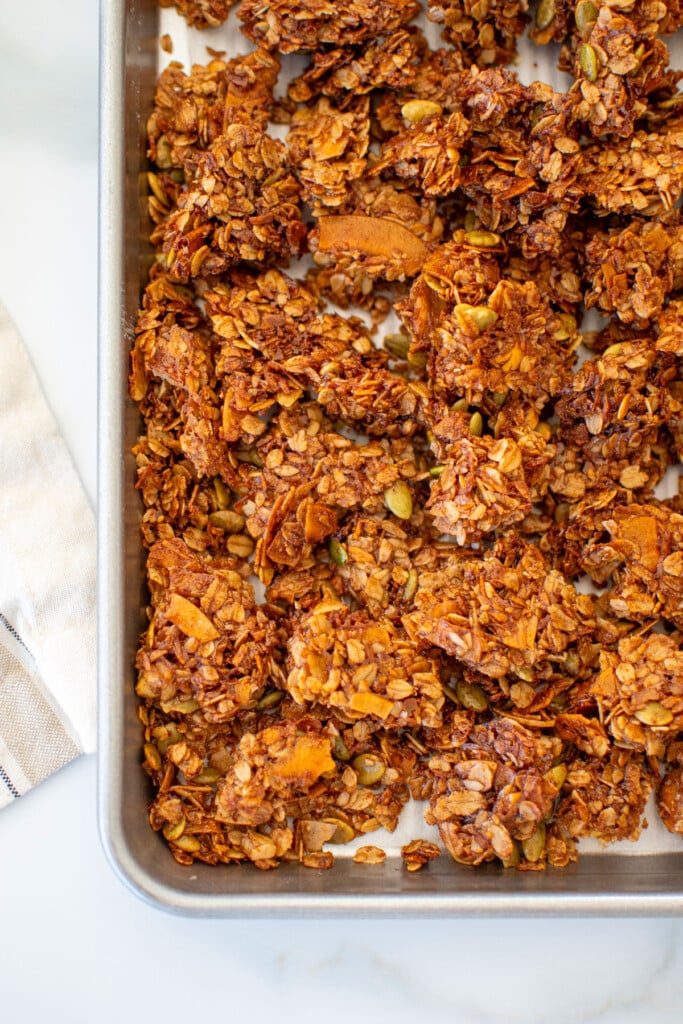 baking sheet of maple cinnamon olive oil granola on a white marble counter.