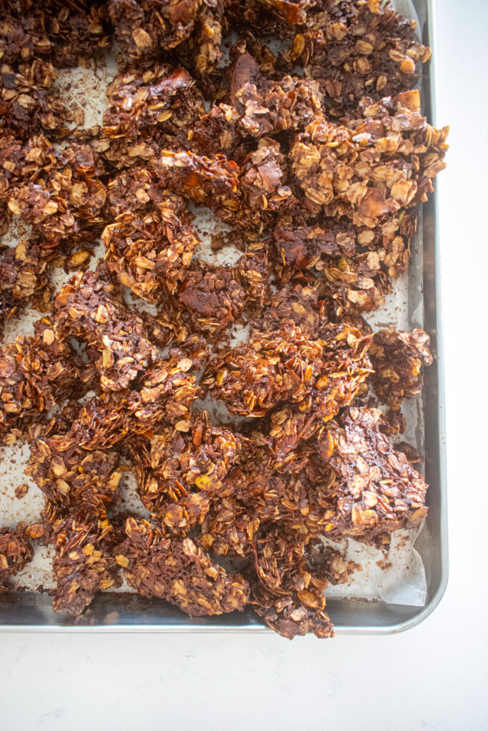 chocolate peppermint olive oil granola clusters on a baking sheet on a marble counter.