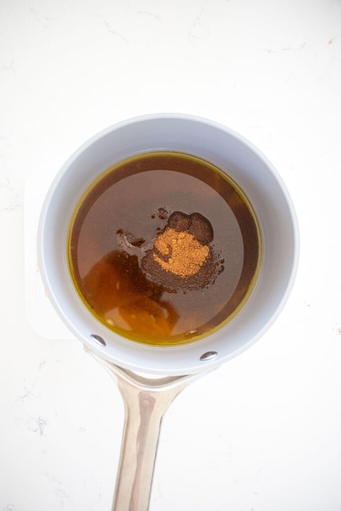 wet ingredients for chocolate peppermint olive oil granola in a small pot on a white marble counter.