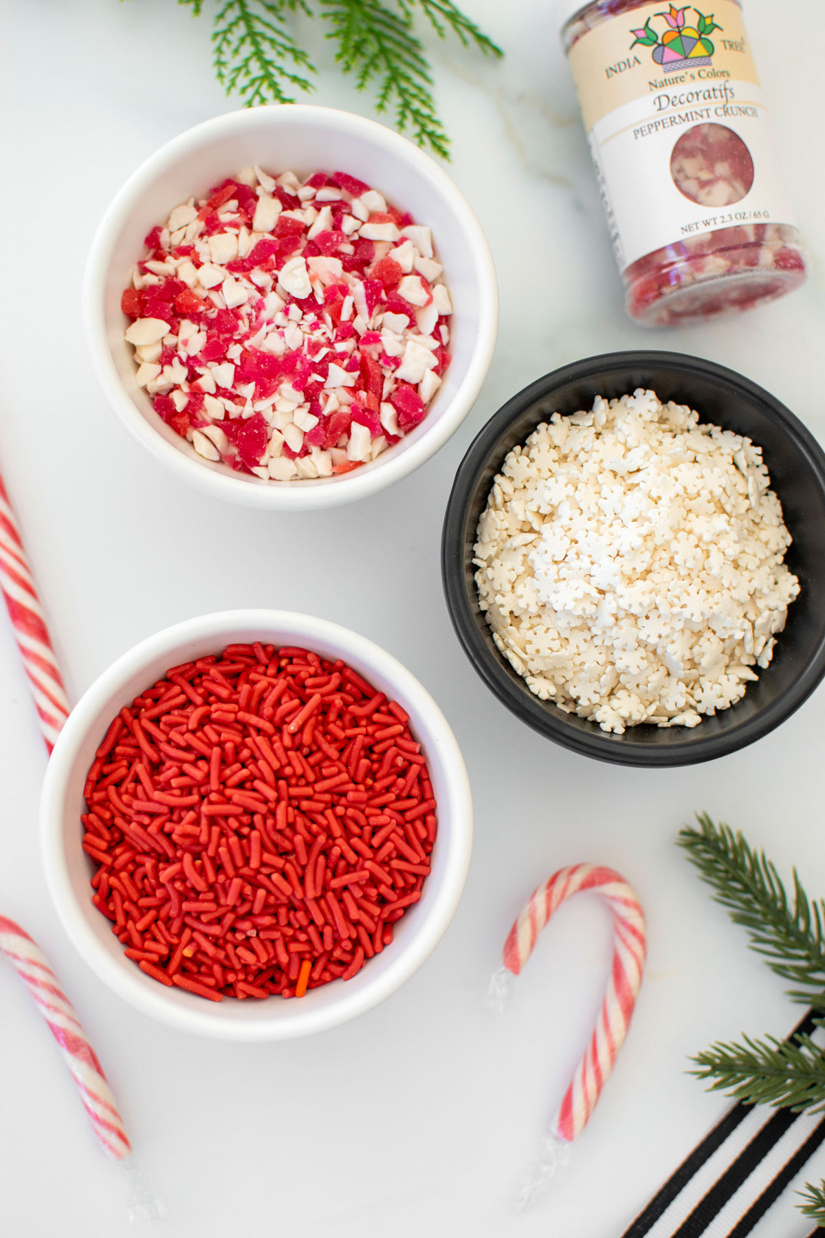 christmas sprinkles in small bowls on a white marble counter.