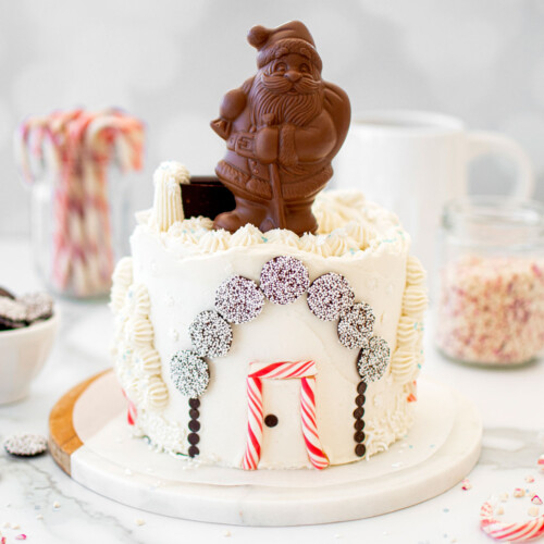christmas eve cake with a chocolate santa on top on a white marble counter.