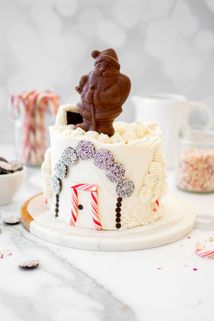 christmas eve cake with a chocolate santa on top on a white marble counter.