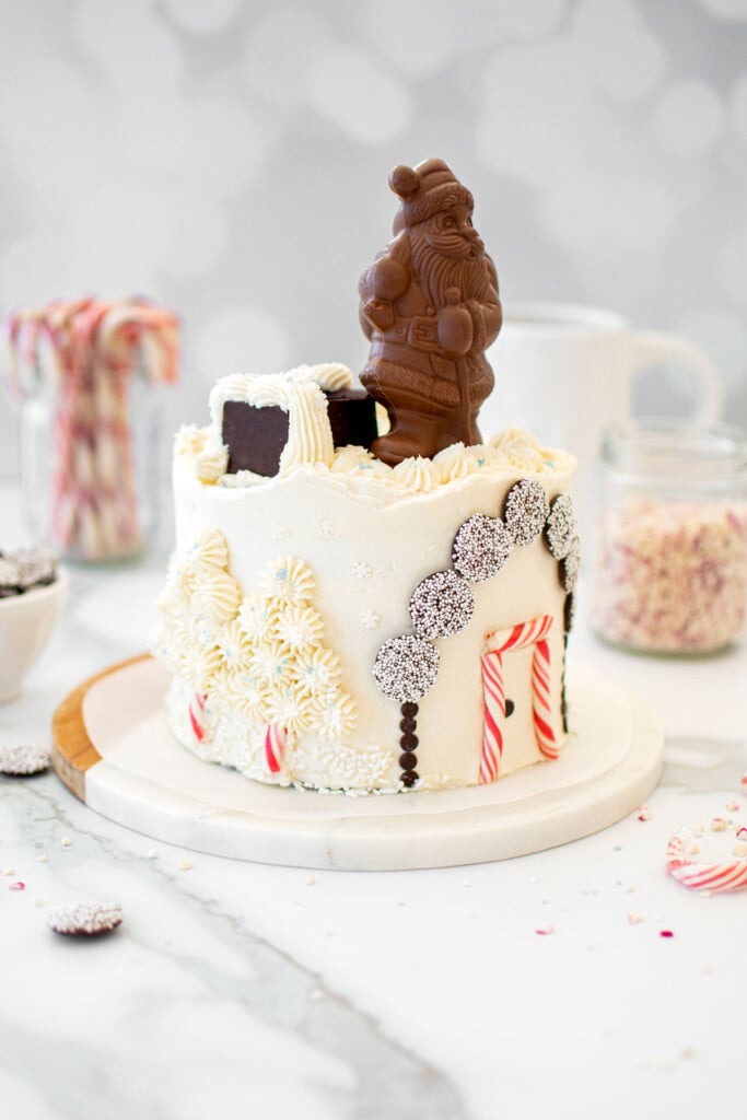 christmas eve cake with a chocolate santa on top on a white marble counter.