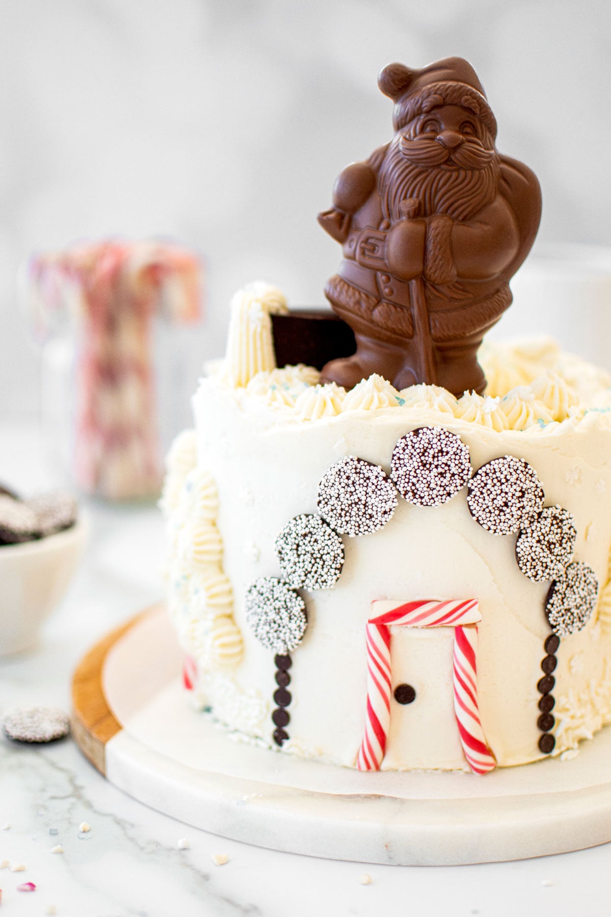 christmas eve cake with a chocolate santa on top on a white marble counter.