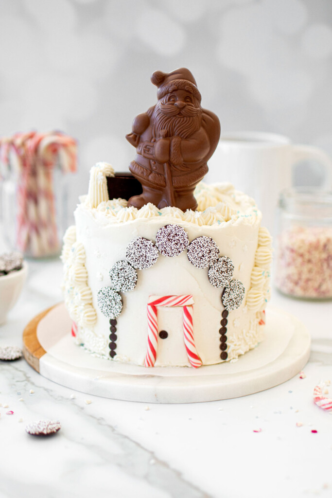 christmas eve cake with a chocolate santa on top on a white marble counter.