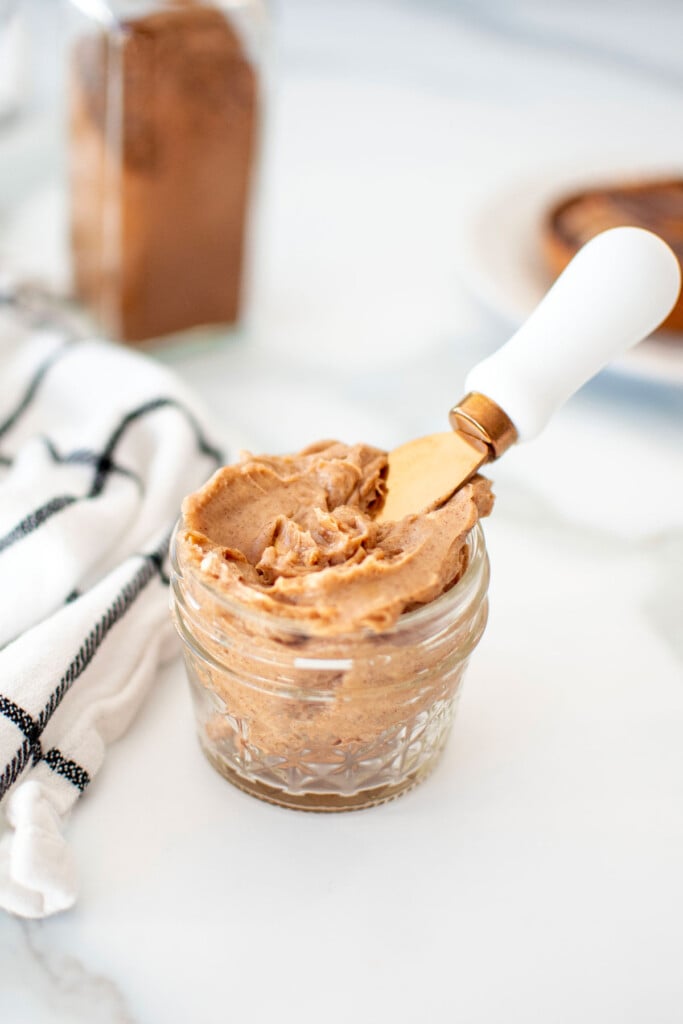 cinnamon honey butter spread in a small glass jar with a small knife on the countertop.