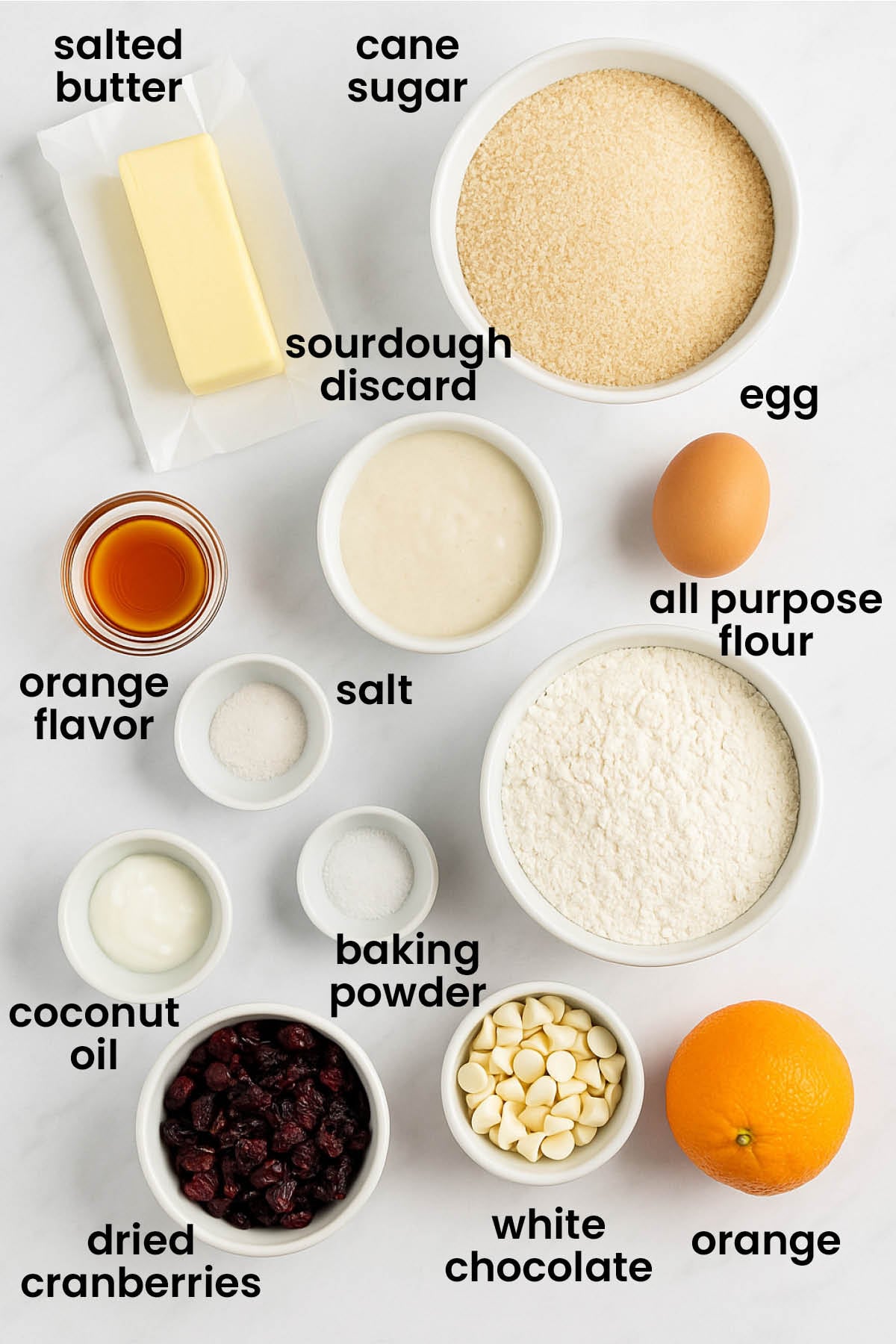 individual ingredients for cranberry orange biscotti with sourdough discard laid out against a white background.
