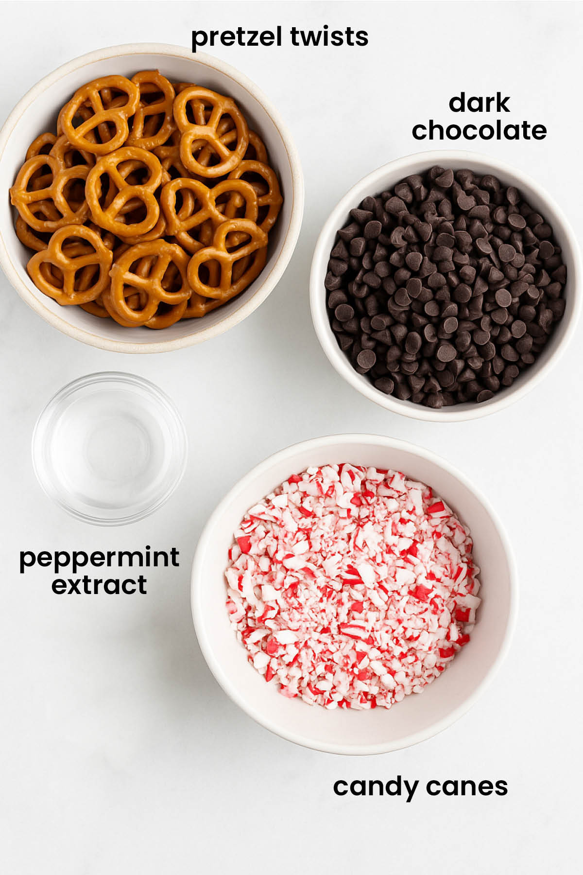 individual ingredients for dark chocolate peppermint pretzel bark laid out against a white background.