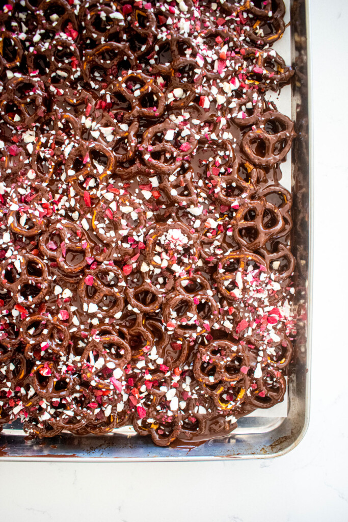 dark chocolate peppermint pretzel bark on a baking sheet on a marble counter.