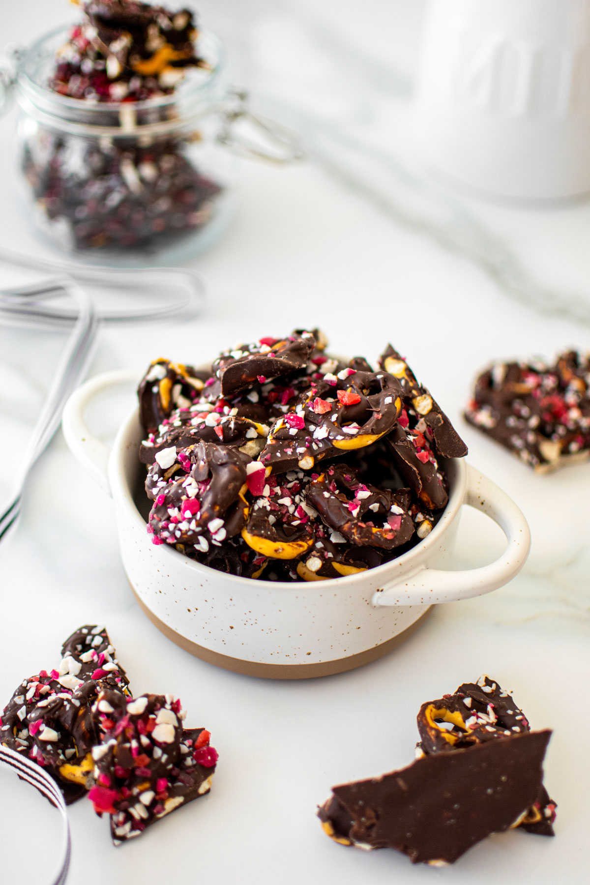 dark chocolate peppermint pretzel bark in a mini dutch oven on a white marble counter.