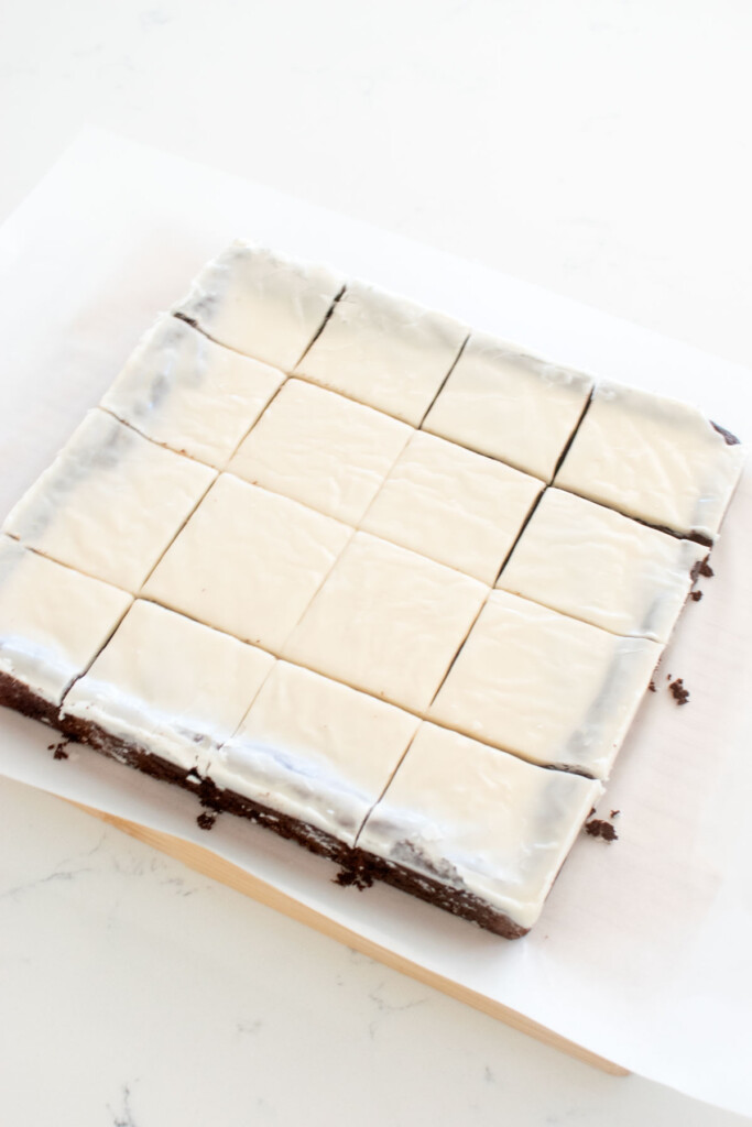 brownies with white icing on top cut into squares on a white marble counter.