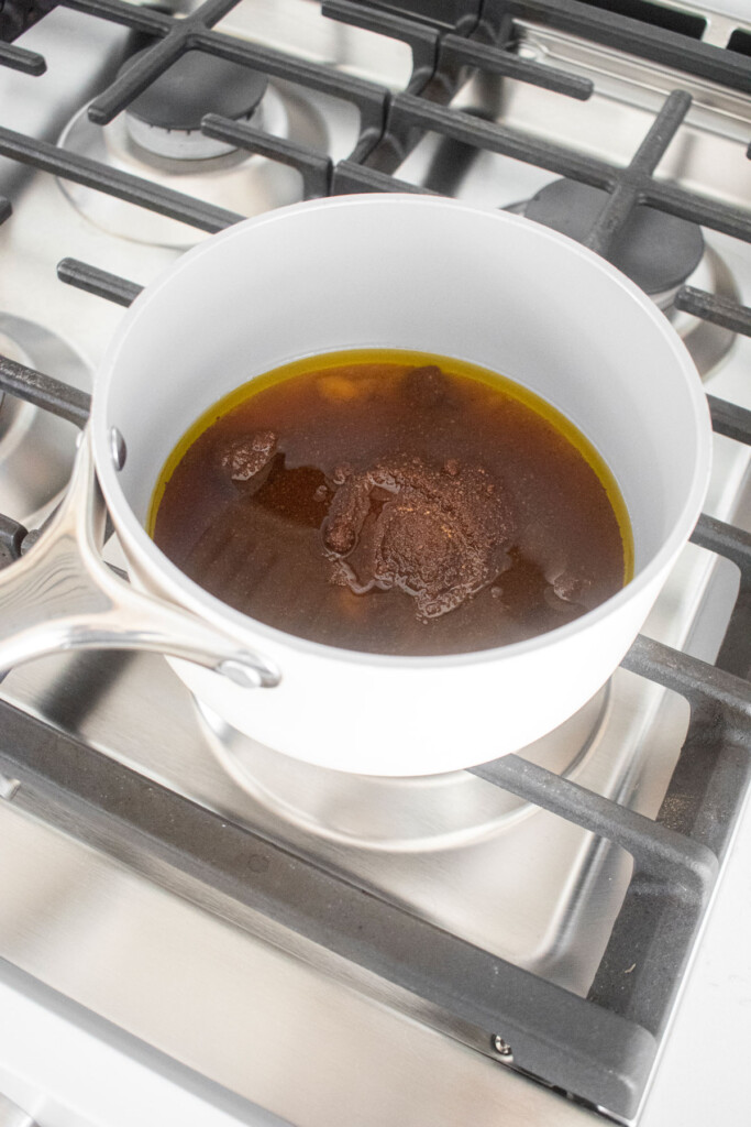 wet ingredients for healthy gingerbread granola in a small pot on the stovetop.