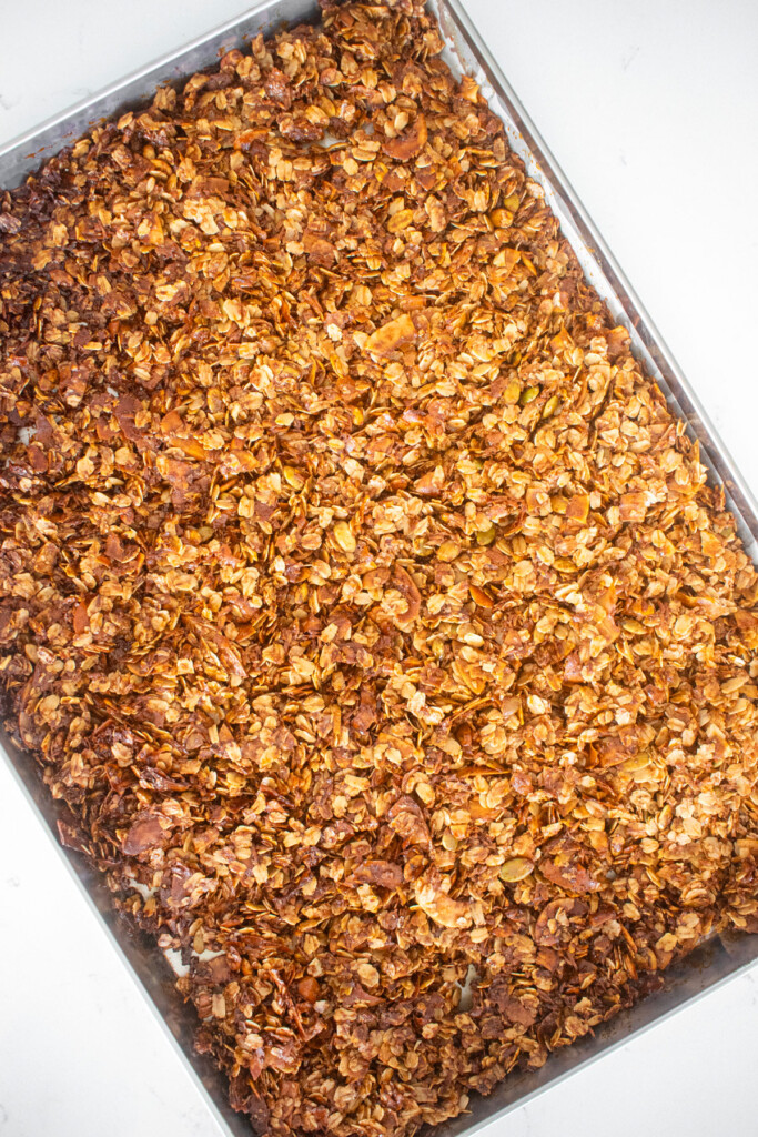 baked healthy gingerbread granola on a baking sheet on a marble counter.