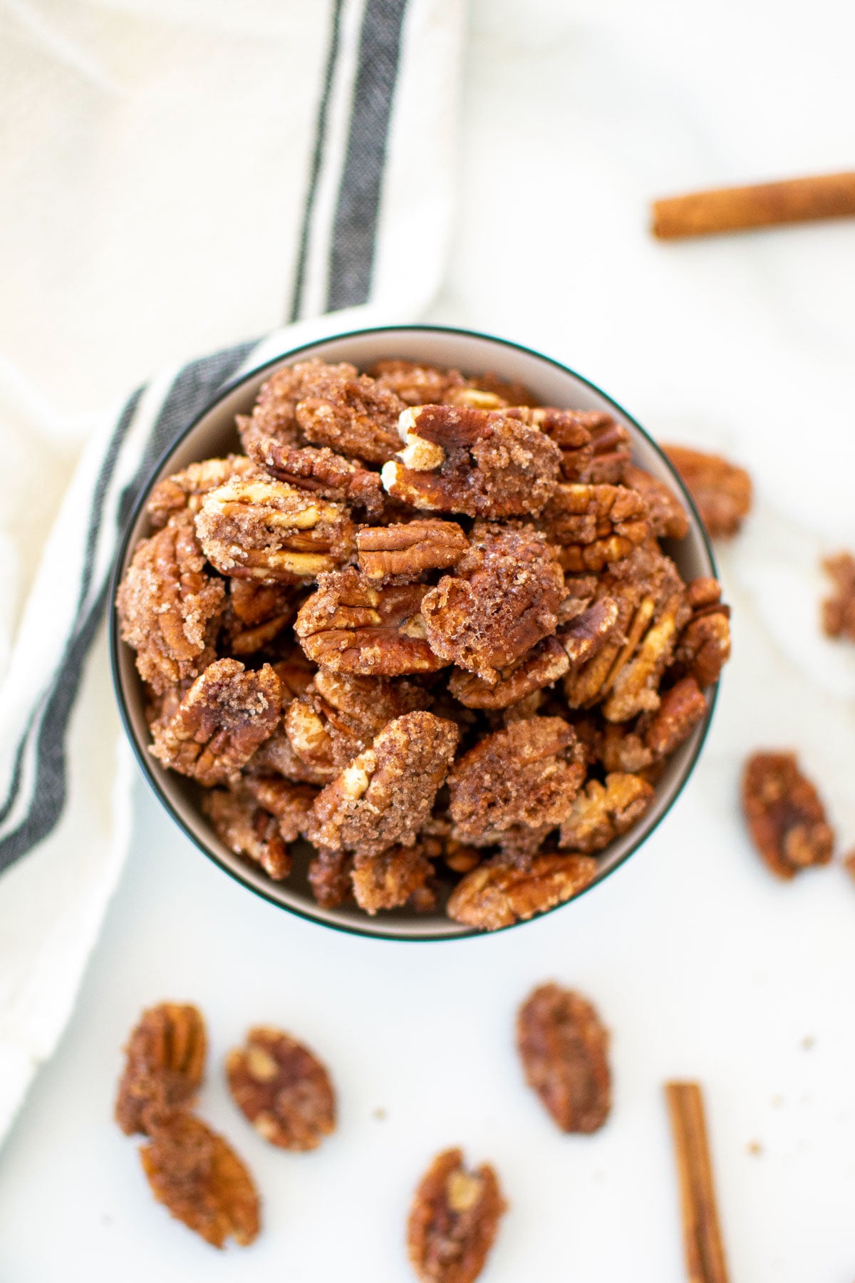 homemade candied pecans without eggs in a bowl on a white marble countertop.