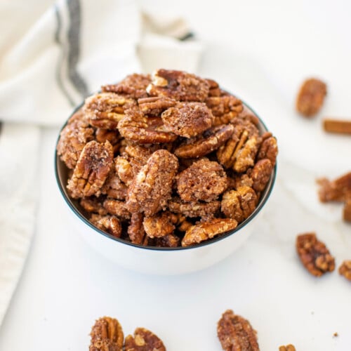 homemade candied pecans without eggs in a bowl on a white marble countertop.