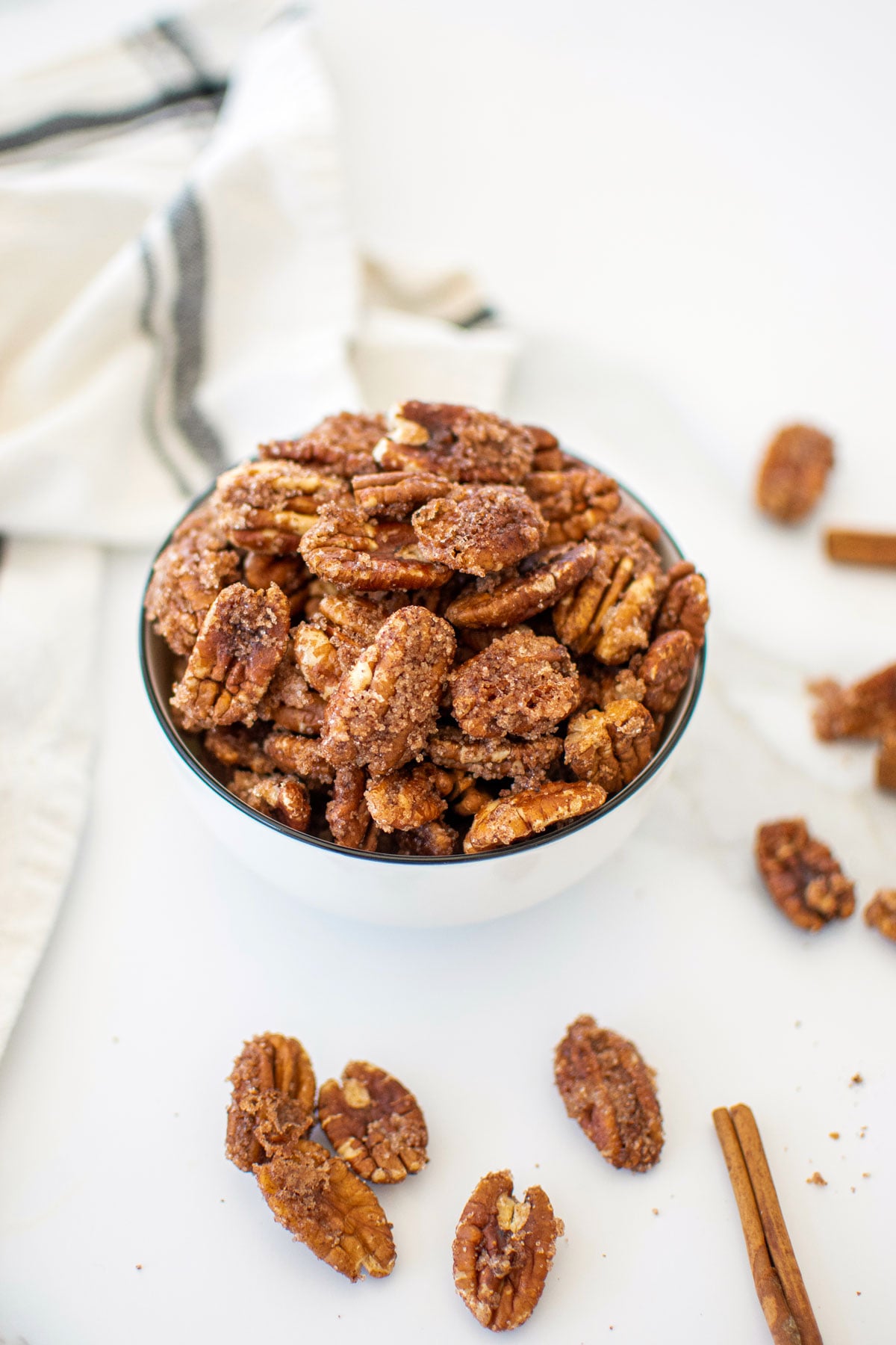 homemade candied pecans without eggs in a bowl on a white marble countertop.