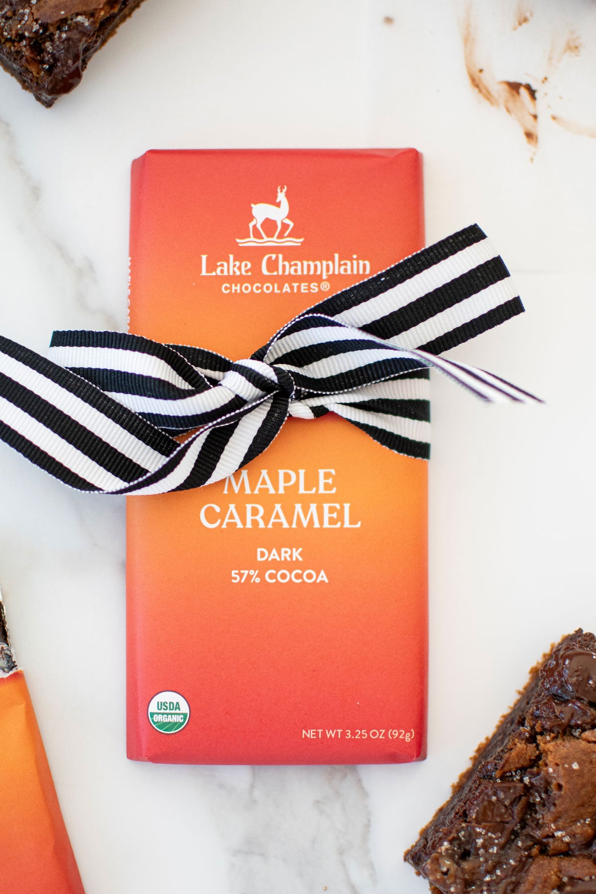 maple caramel dark chocolate bar with a ribbon around it on a white marble counter.