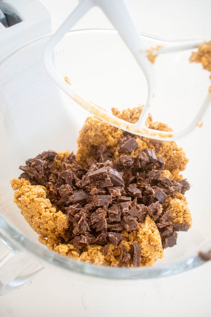 maple caramel dark chocolate gingerbread cookie dough in a glass mixing bowl on a white marble counter.
