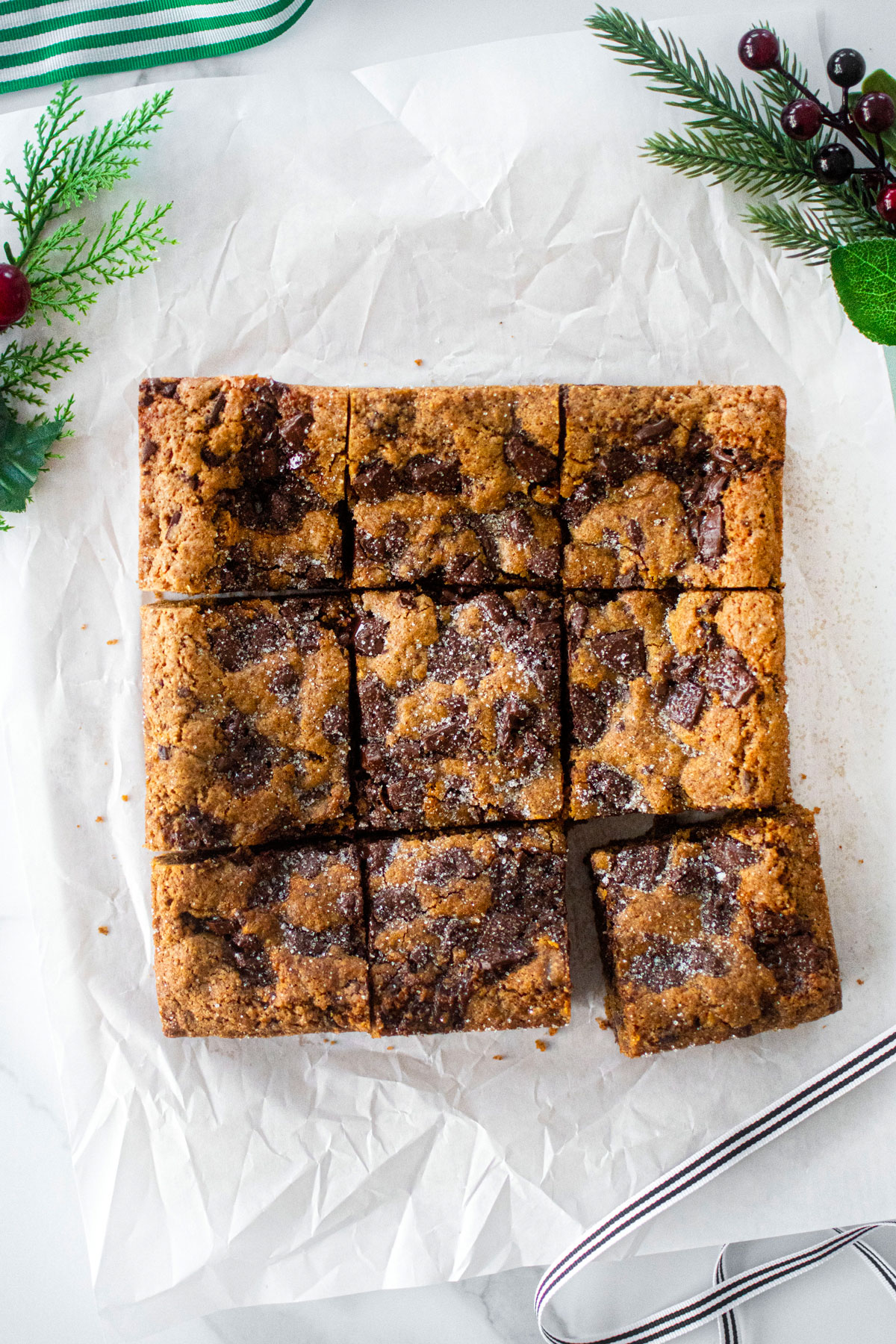 maple caramel dark chocolate gingerbread cookie bars cut into squares on a white marble counter.