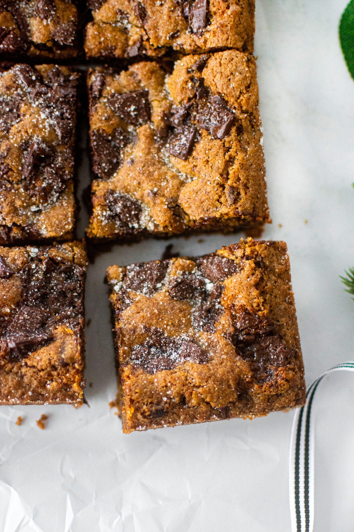 maple caramel dark chocolate gingerbread cookie bars cut into squares on a white marble counter.