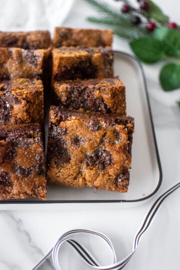 maple caramel dark chocolate gingerbread cookie bars on a white platter on a marble counter.