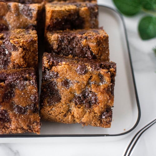 maple caramel dark chocolate gingerbread cookie bars on a white platter on a marble counter.