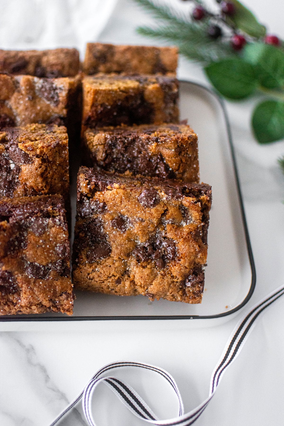 maple caramel dark chocolate gingerbread cookie bars on a white platter on a marble counter.