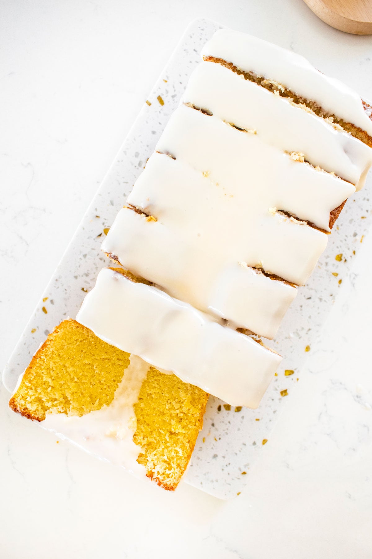 meyer lemon pound cake loaf cut into slices on a white marble counter.