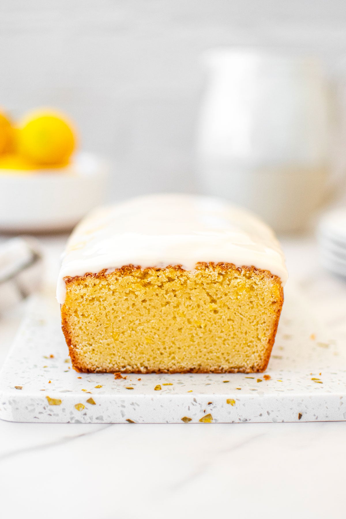 meyer lemon pound cake loaf on a white marble counter with fresh lemeons.