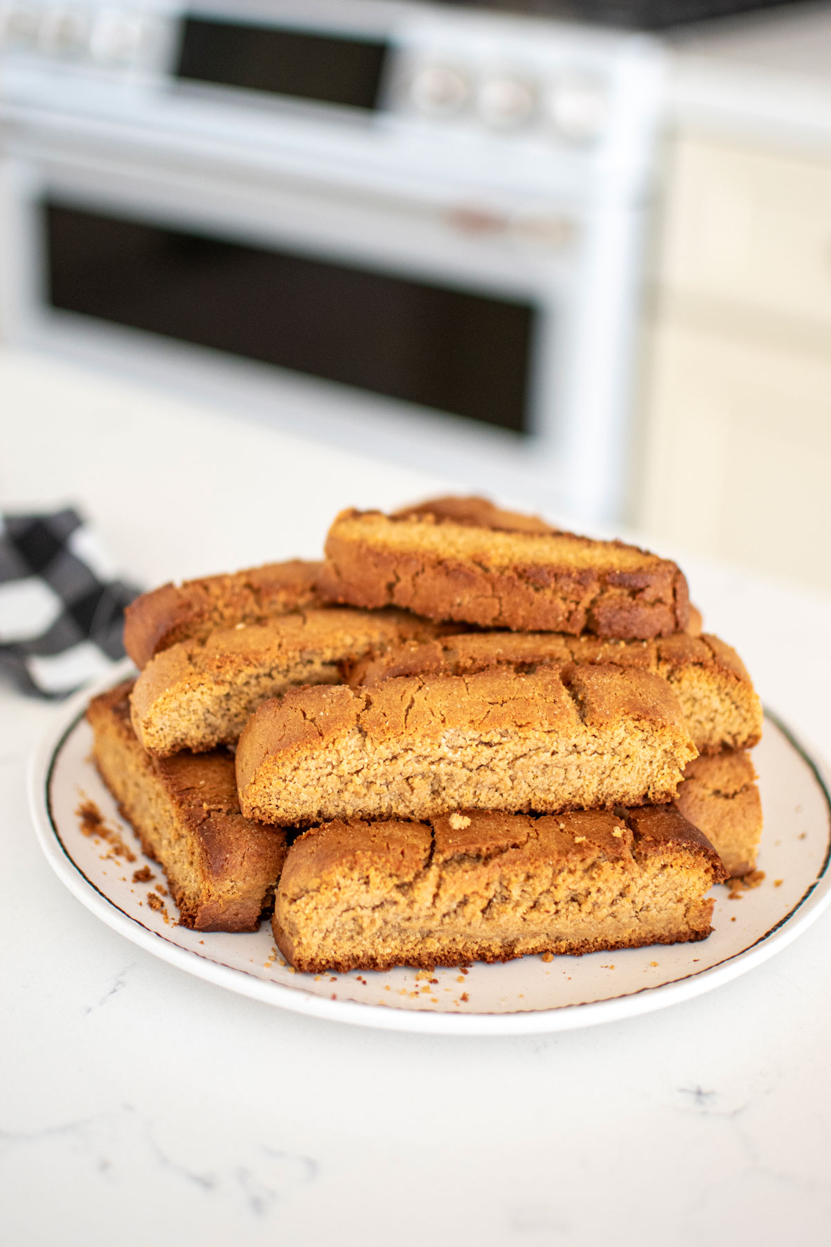 peanut butter biscotti for dogs on a plate on a white marble kitchen counter.