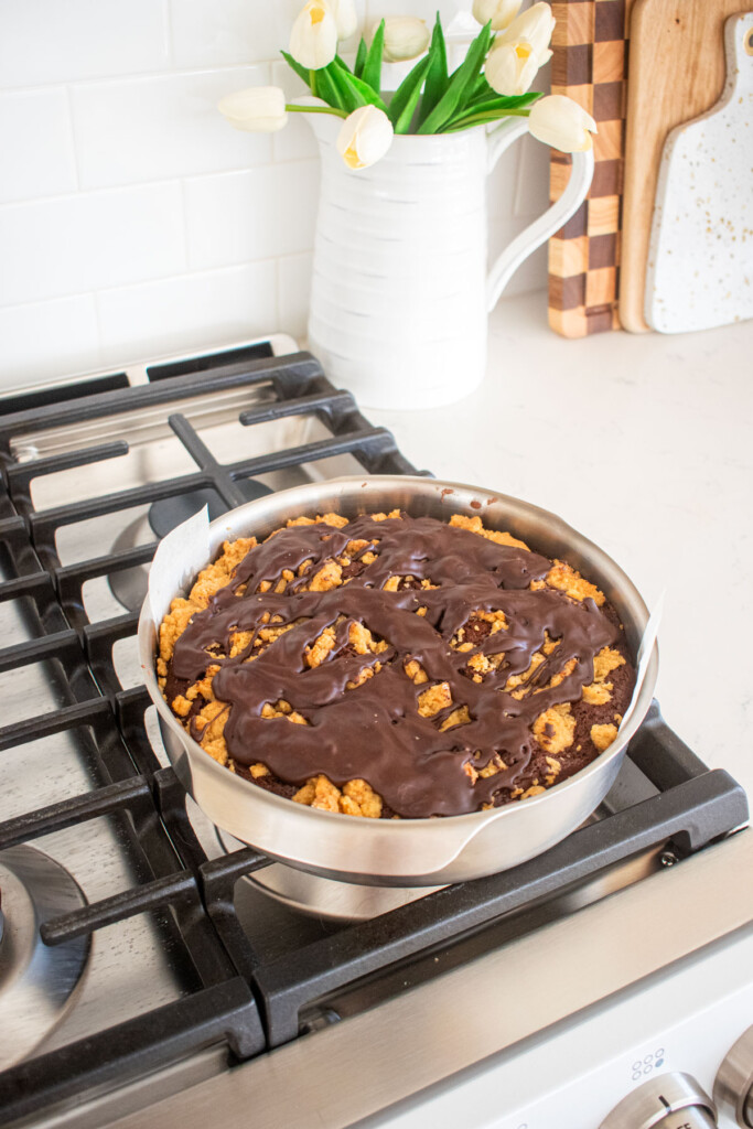 peppermint mocha coffee cake with glaze on in a cake pan sitting on top of a stovetop.