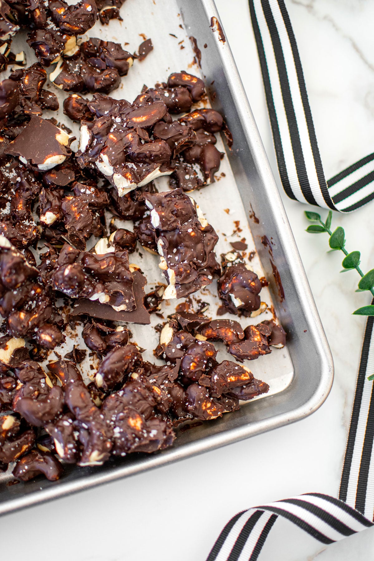 sea salt dark chocolate cashew clusters broken into clusters on a baking sheet on a marble counter.