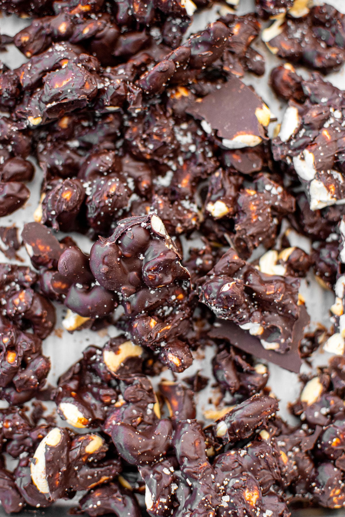 sea salt dark chocolate cashew clusters broken into clusters on a baking sheet.