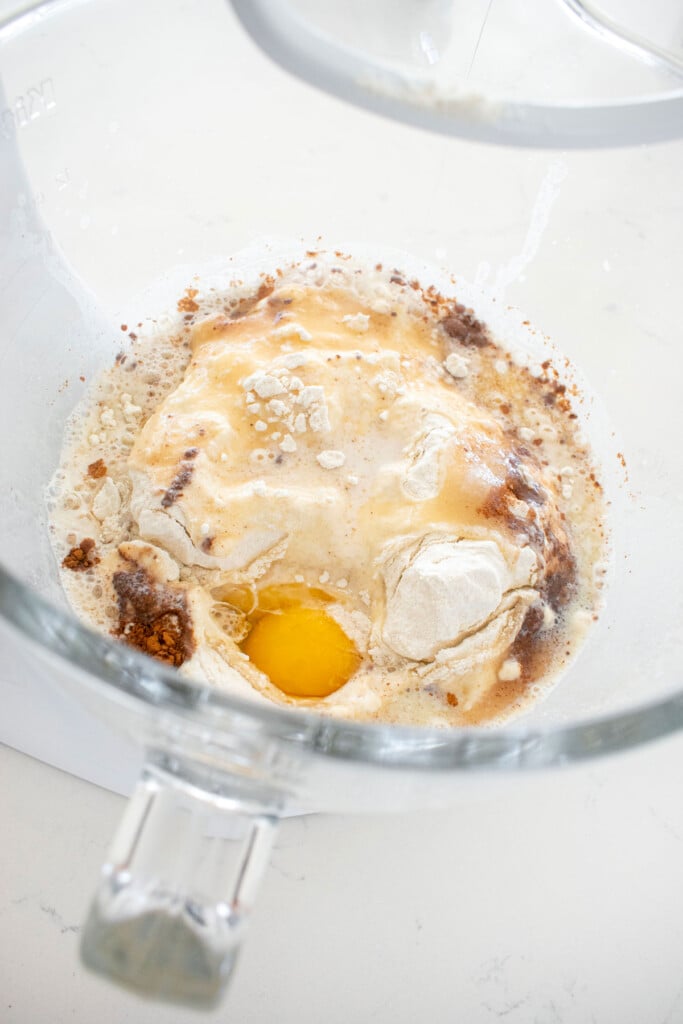 spiced eggnog babka bun ingredients in a glass mixing bowl on a marble counter.